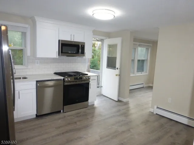 a kitchen with granite countertop white cabinets and stainless steel appliances