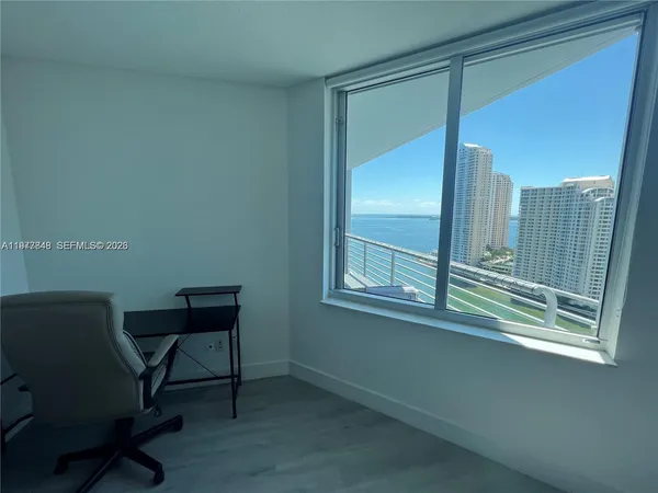 a view of a workspace room with wooden floor and a window