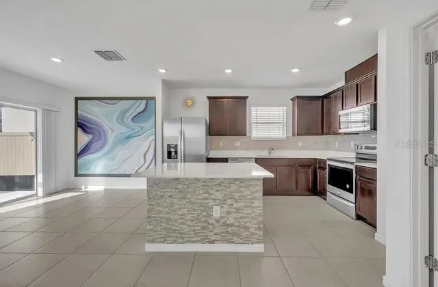 a large kitchen with stainless steel appliances kitchen island granite countertop a refrigerator and a stove top oven