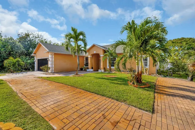 a front view of a house with a yard and potted plants