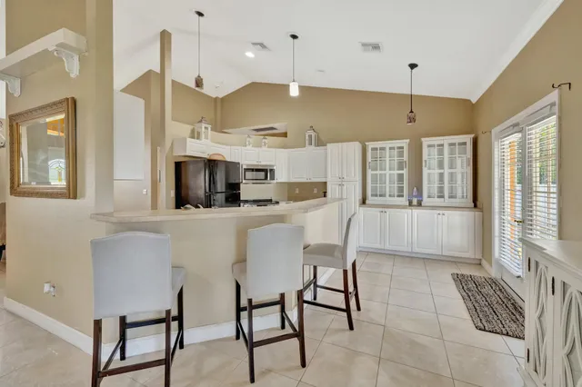 a kitchen with stainless steel appliances kitchen island granite countertop a table chairs and a refrigerator
