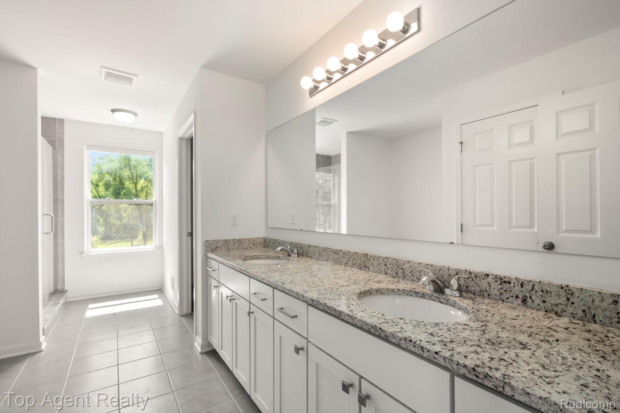 63770 Dequindre Road Washington, MI 48095 - Photo 43 of 61 Double vanity with speckled stone countertop and white cabinetry, featuring dual undermount sinks and chrome fixtures