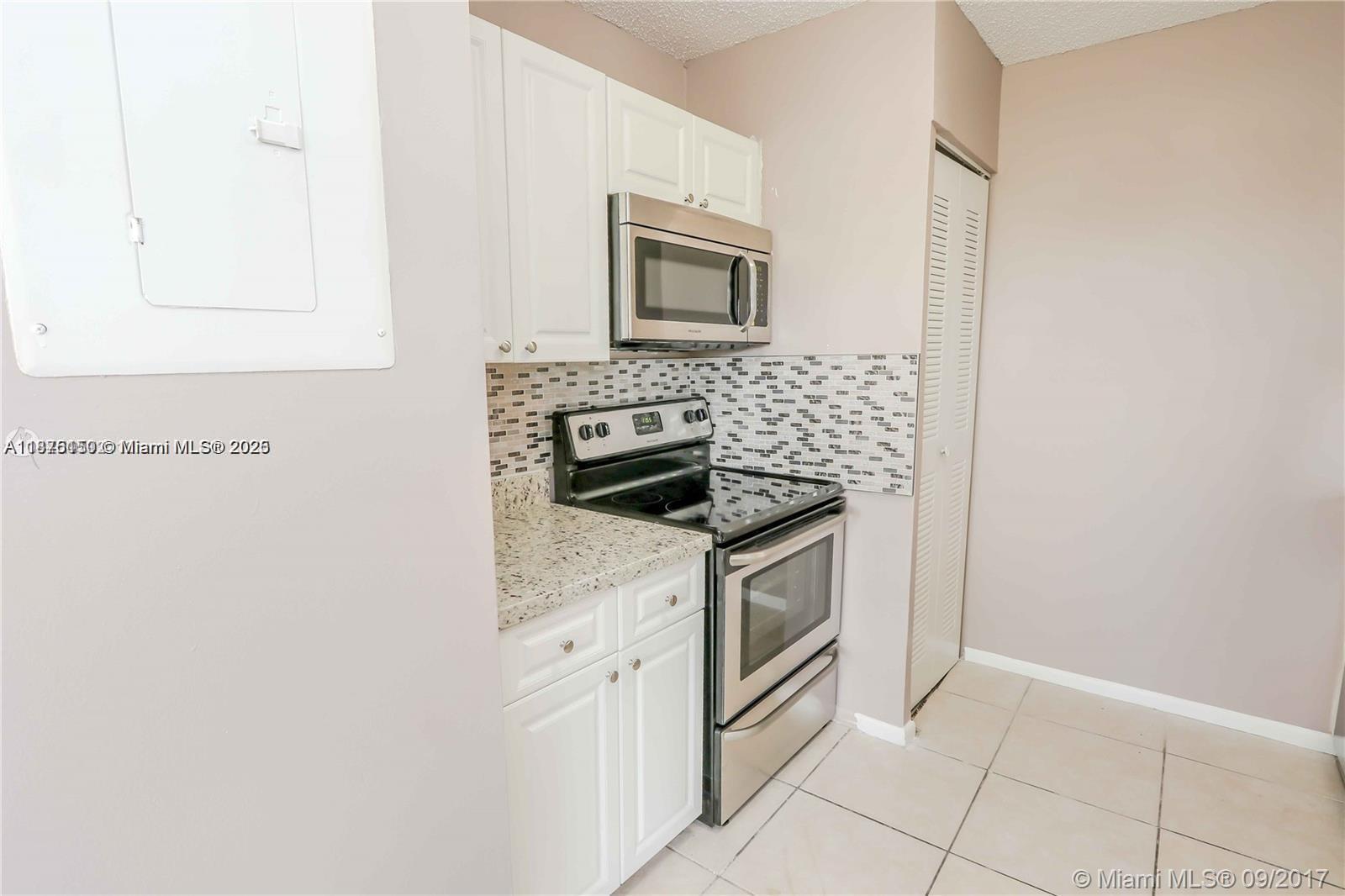 8734 Southwest 3rd Street, Unit 206 Pembroke Pines, FL 33025 - Photo 5 of 14 a kitchen with granite countertop white cabinets and white appliances