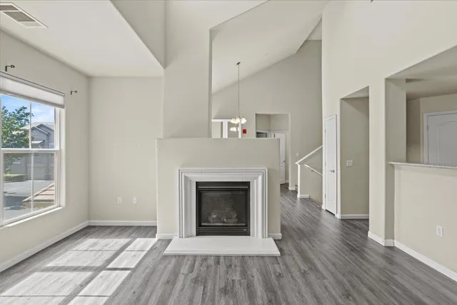 an empty room with wooden floor a ceiling fan and windows