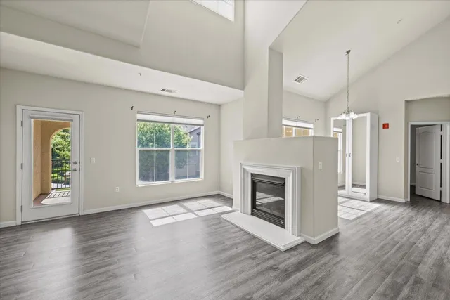 an empty room with wooden floor a ceiling fan and windows
