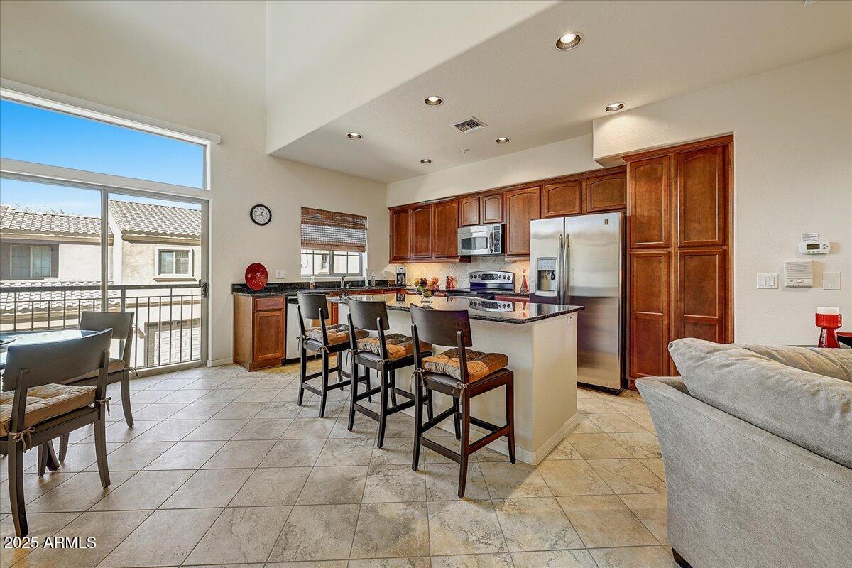 3935 East Rough Rider Road, Unit 1191 Phoenix, AZ 85050 - Photo 4 of 32 a kitchen with stainless steel appliances kitchen island granite countertop a refrigerator and cabinets