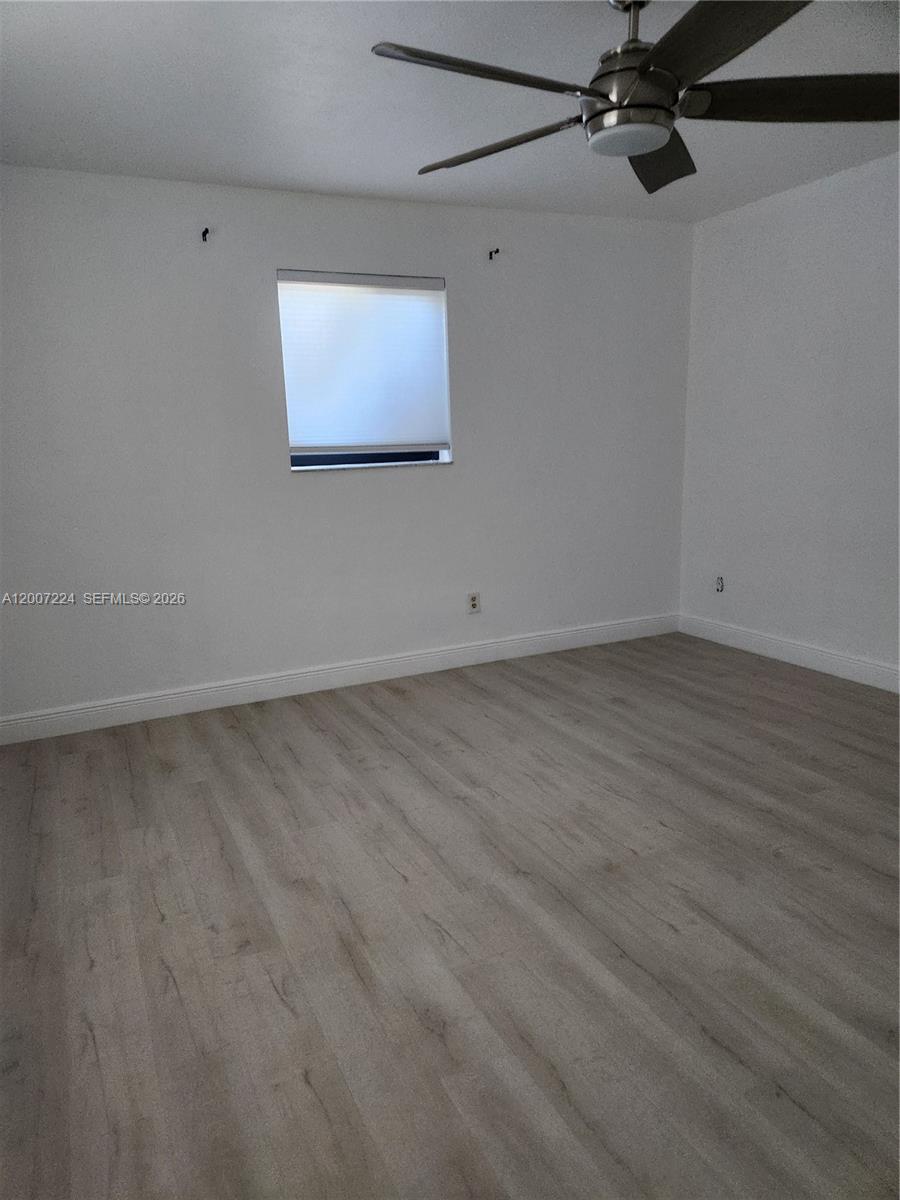 11025 Southwest 138th Court, Unit 11025 Miami, FL 33186 - Photo 16 of 21 an empty room with wooden floor and windows