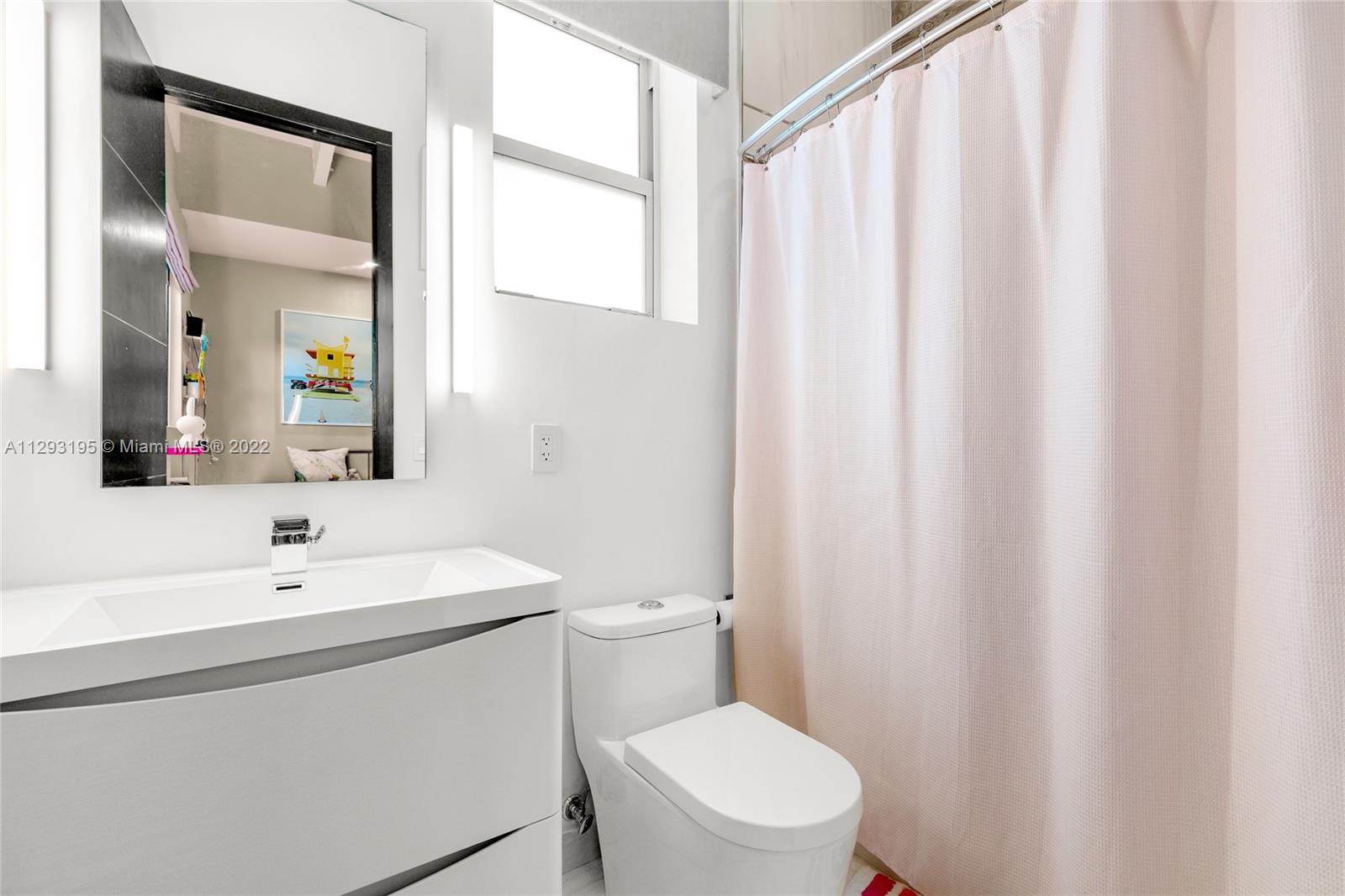 1666 Tigertail Avenue Miami, FL 33133 - Photo 27 of 41 a bathroom with a sink a toilet and shower curtain
