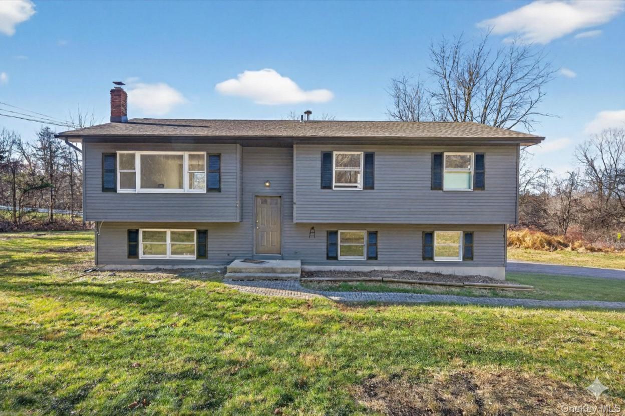 Raised ranch with a chimney, a front lawn, and roof with shingles