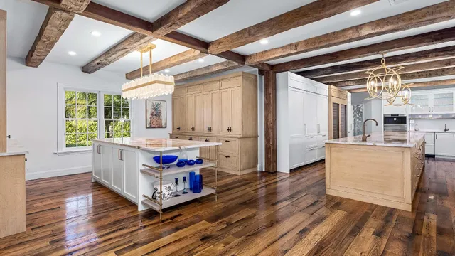 a room with kitchen island granite countertop wooden floors and a sink