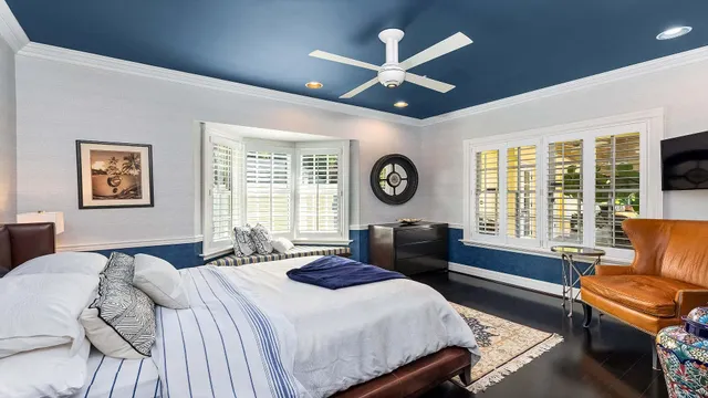 a bedroom with a bed a couch and a large window with the outer view