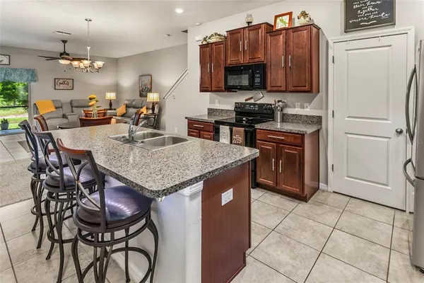 a kitchen with stainless steel appliances granite countertop a stove a refrigerator a sink a dining table and chairs with wooden floor