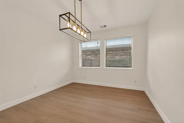 an empty room with wooden floor windows and ceiling fan