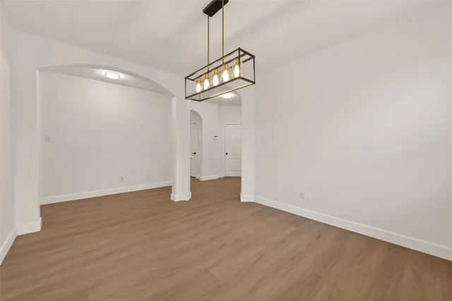 a view of an empty room with wooden floor and a ceiling fan