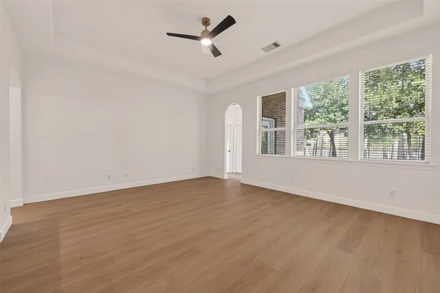 a view of an empty room with a window and wooden floor
