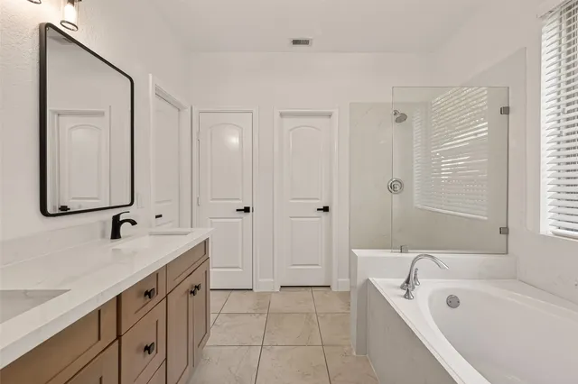 a spacious bathroom with a tub sink and mirror
