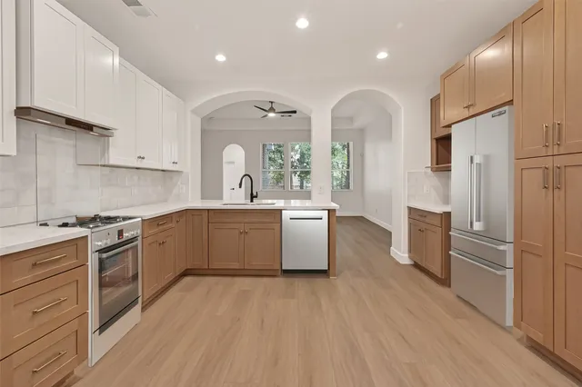 a large kitchen with stainless steel appliances granite countertop a lot of counter space and wooden floors