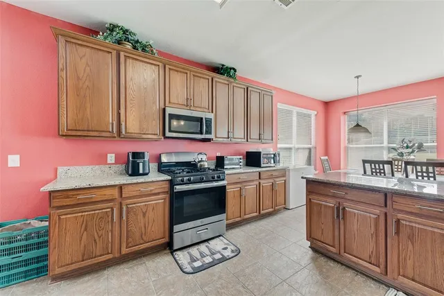 a kitchen with stainless steel appliances granite countertop a stove a sink dishwasher and a microwave oven with cabinets