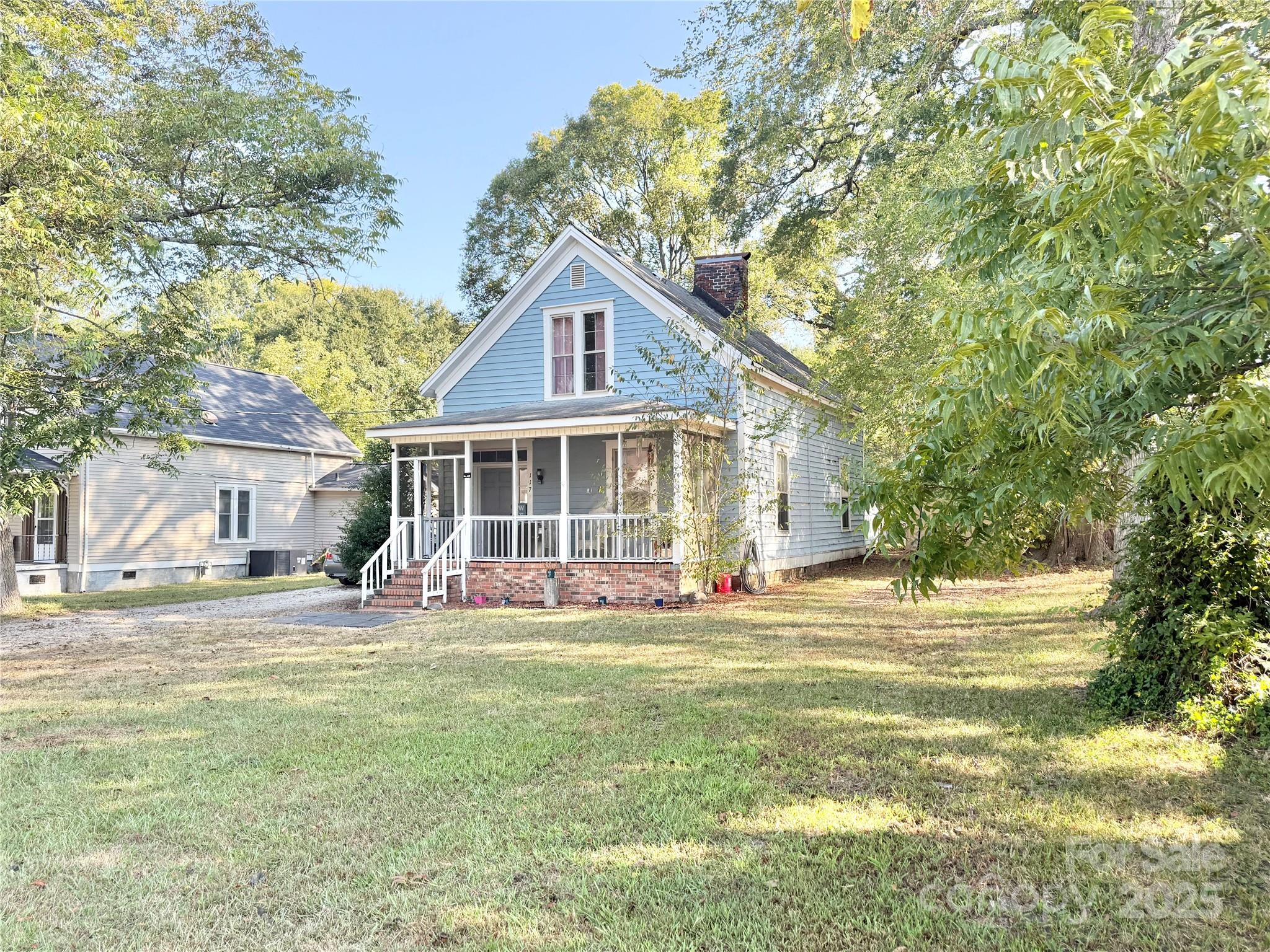 a front view of a house with a garden and trees