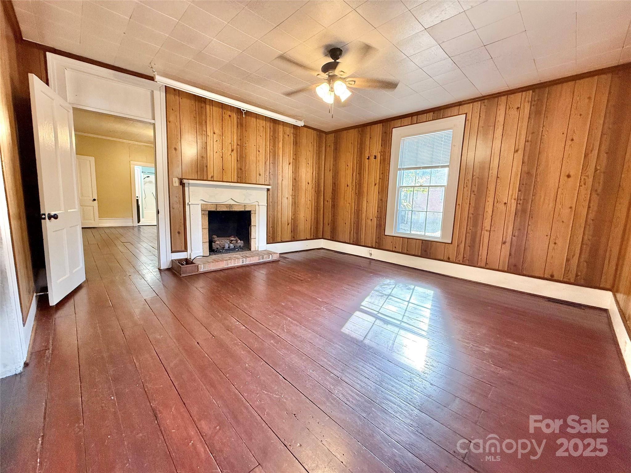 117 Pine Street Chester, SC 29706 - Photo 8 of 19 an empty room with wooden floor fireplace fan and windows