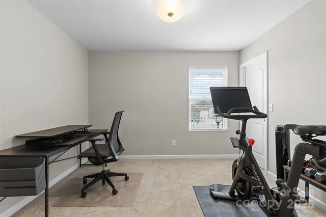 a view of a workspace with furniture and a gym cycle