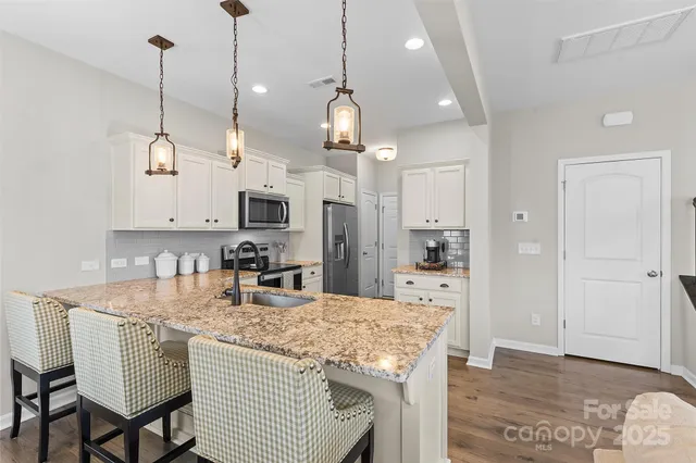 a kitchen with granite countertop kitchen island white cabinets and refrigerator