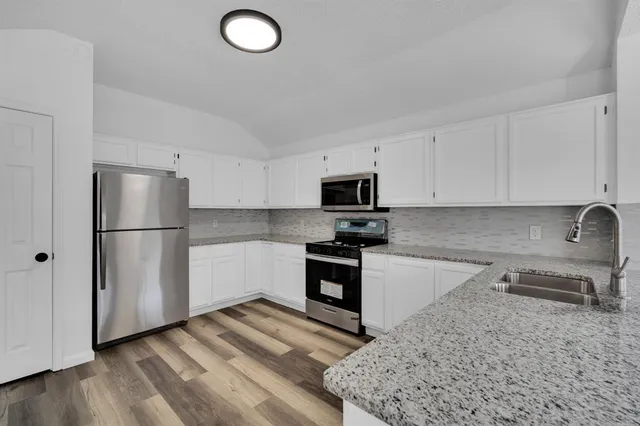 a kitchen with stainless steel appliances granite countertop a refrigerator sink and stove
