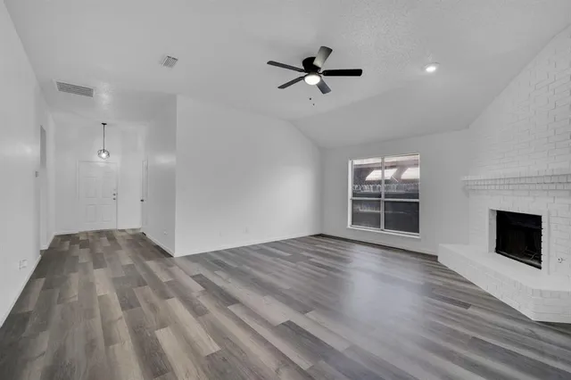 a view of empty room with wooden floor and fireplace
