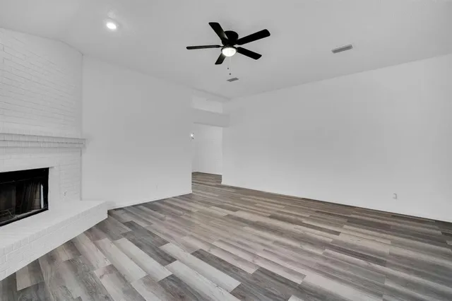 a view of empty room with wooden floor and a ceiling fan
