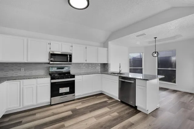 a kitchen with stainless steel appliances a stove a sink and white cabinets