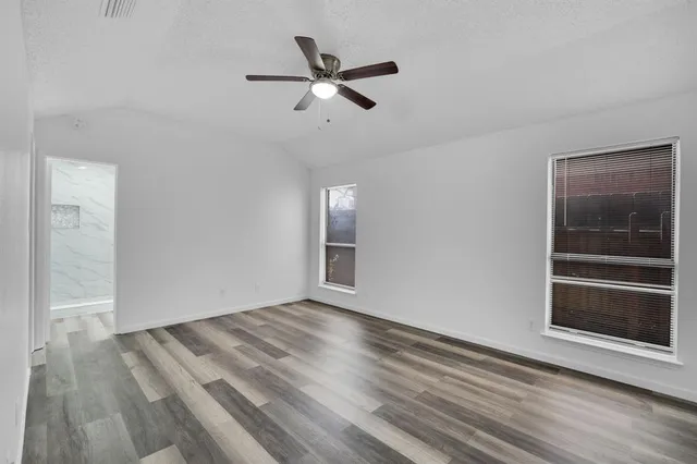 a view of empty room with wooden floor and ceiling fan