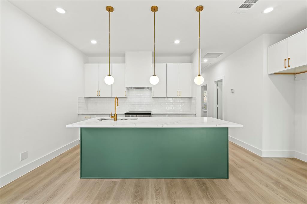 4827 Baldwin Street Dallas, TX 75210 - Photo 4 of 21 a large kitchen with kitchen island a stove a sink a center island and wooden floor