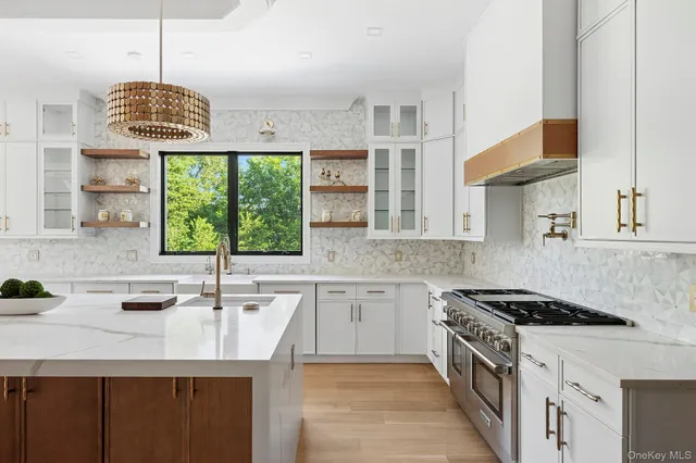 a kitchen with stainless steel appliances granite countertop a sink a stove a counter space and a window