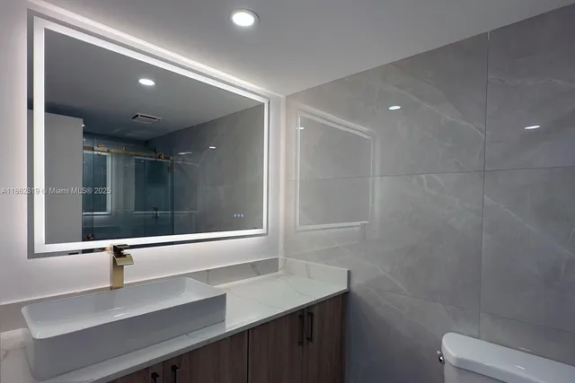 a bathroom with a sink a toilet a mirror and shower