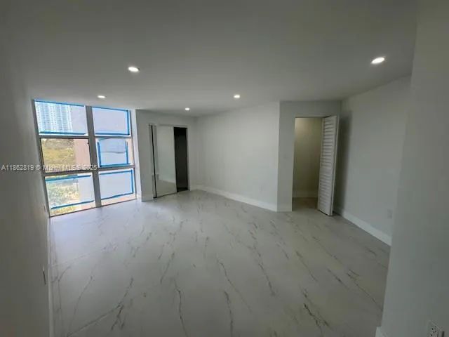 an empty room with windows and cabinet
