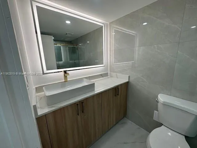 a bathroom with a sink a toilet a mirror and shower