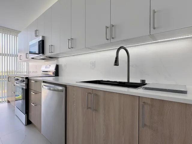 a kitchen with stainless steel appliances a sink dishwasher a refrigerator and cabinets