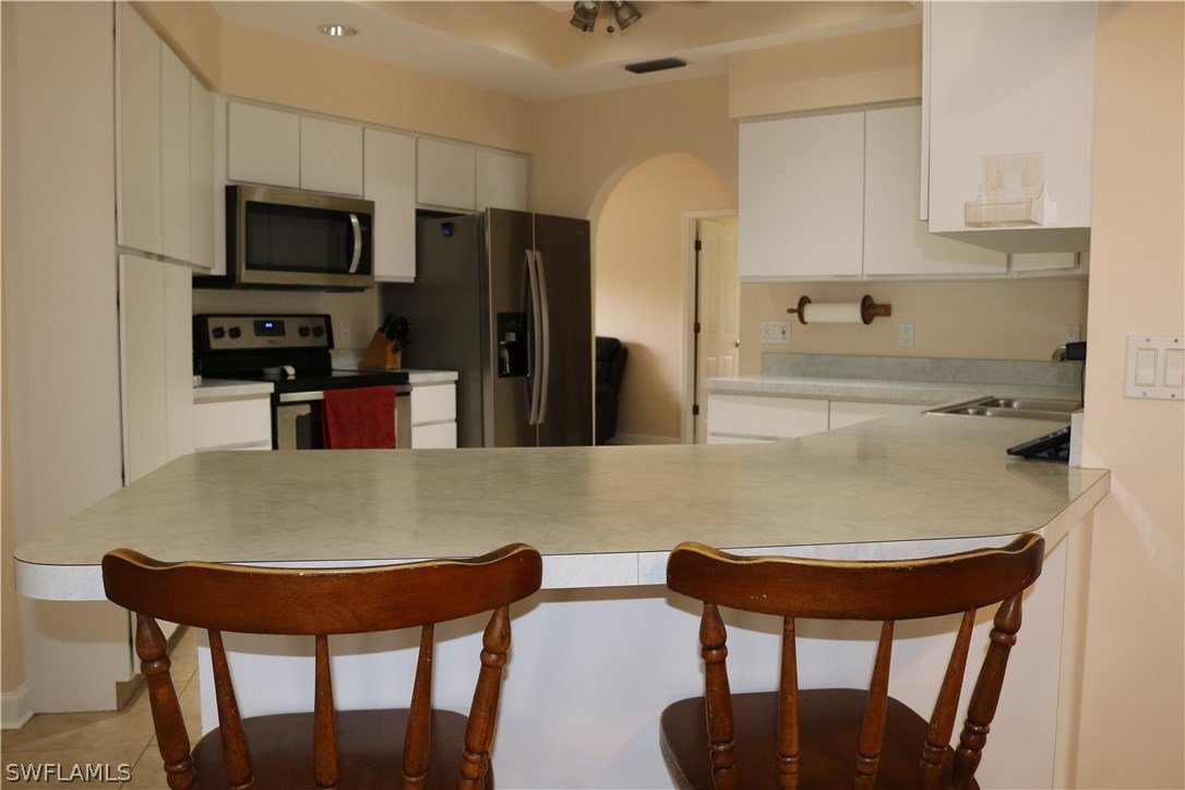 18432 Olive Road Fort Myers, FL 33967 - Photo 7 of 18 a kitchen with stainless steel appliances granite countertop a dining table chairs refrigerator and microwave