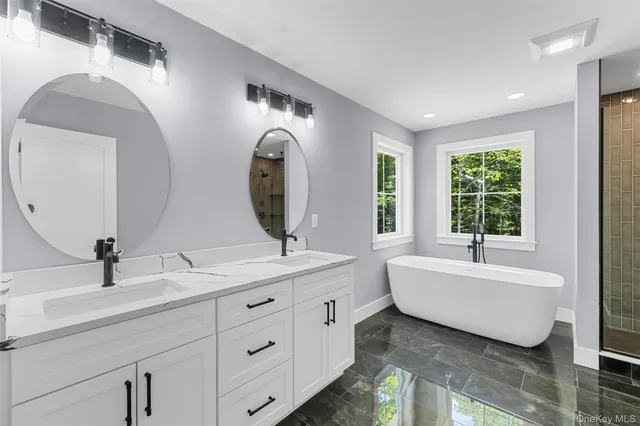 a spacious bathroom with a double vanity sink mirror and bathtub