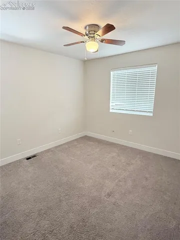 an empty room with a window and a ceiling fan