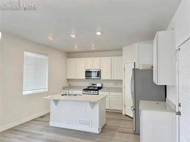 a kitchen with a refrigerator and a stove top oven
