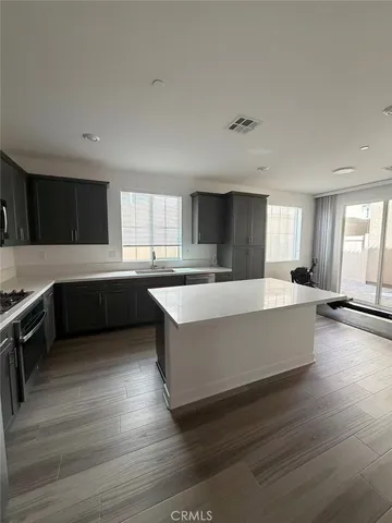 a large room with kitchen island wooden floors and stainless steel appliances