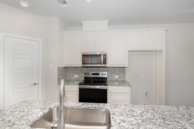 a kitchen with stainless steel appliances granite countertop a stove and a refrigerator