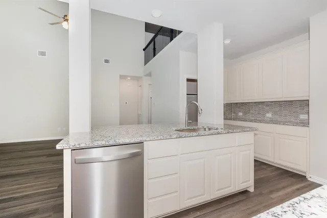 a kitchen with stainless steel appliances white cabinets and wooden floor