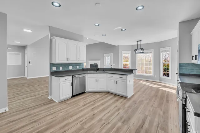a kitchen with granite countertop a white stove top oven and white cabinets