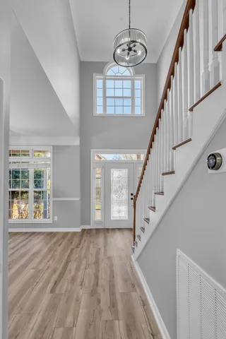 a view of staircase with wooden floor and pendant lights