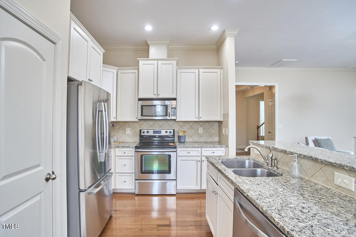 808 Historian Street Raleigh, NC 27603 - Photo 19 of 51 a kitchen with stainless steel appliances granite countertop a refrigerator a stove and a sink with wooden floor