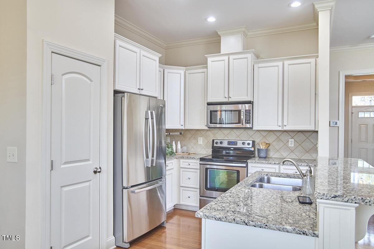808 Historian Street Raleigh, NC 27603 - Photo 21 of 51 a kitchen with stainless steel appliances granite countertop a refrigerator a stove and white cabinets with wooden floor