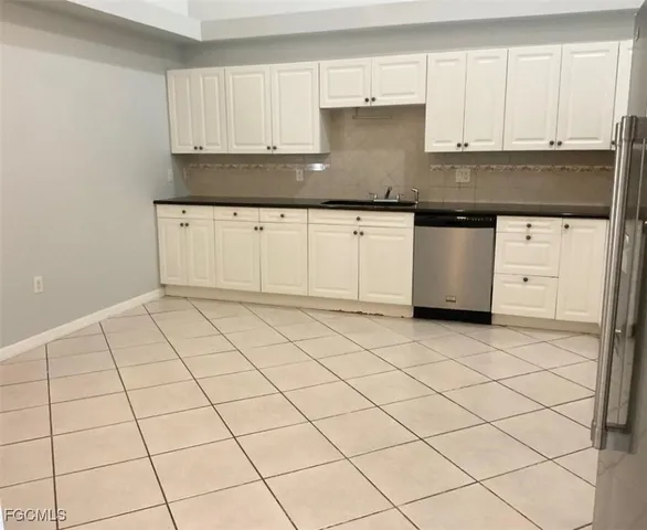 a kitchen with granite countertop a sink and white cabinets
