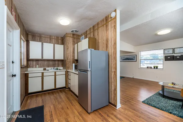a kitchen with a refrigerator cabinets and wooden floor